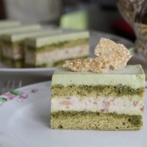 a slice of matcha red bean mousse cake on decorative white tea plate.