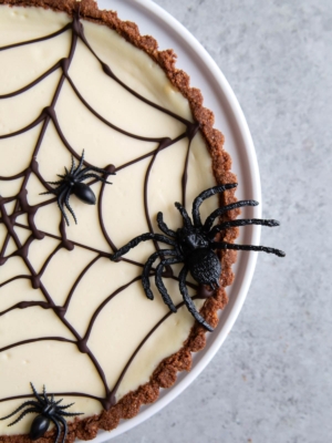 chocolate spider web cheesecake tart decorated with plastic spiders.