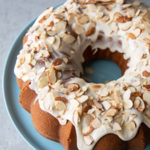 almond pound cake with almond glaze and toasted sliced almonds on blue plate.