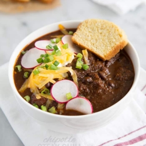 Chipotle Steak Chili topped with sliced radish, shredded cheese, and green onions