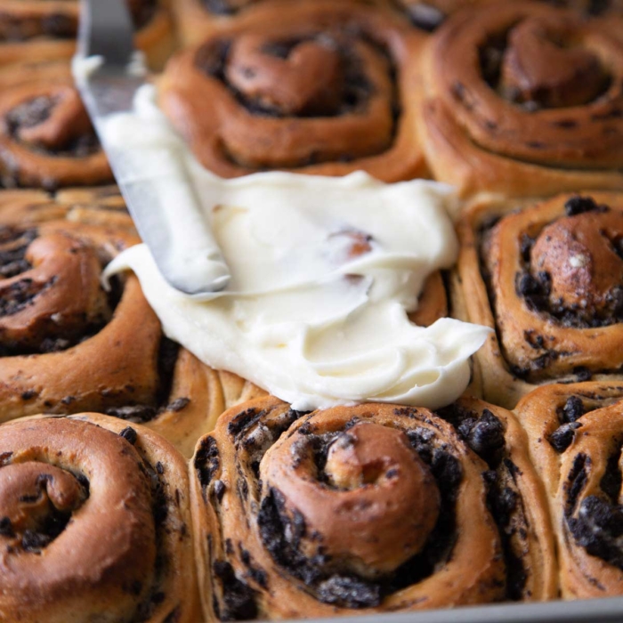 spread cream cheese frosting over baked rolls.