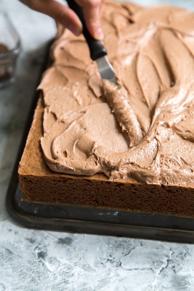 spread chocolate buttercream over chocolate sheet cake.