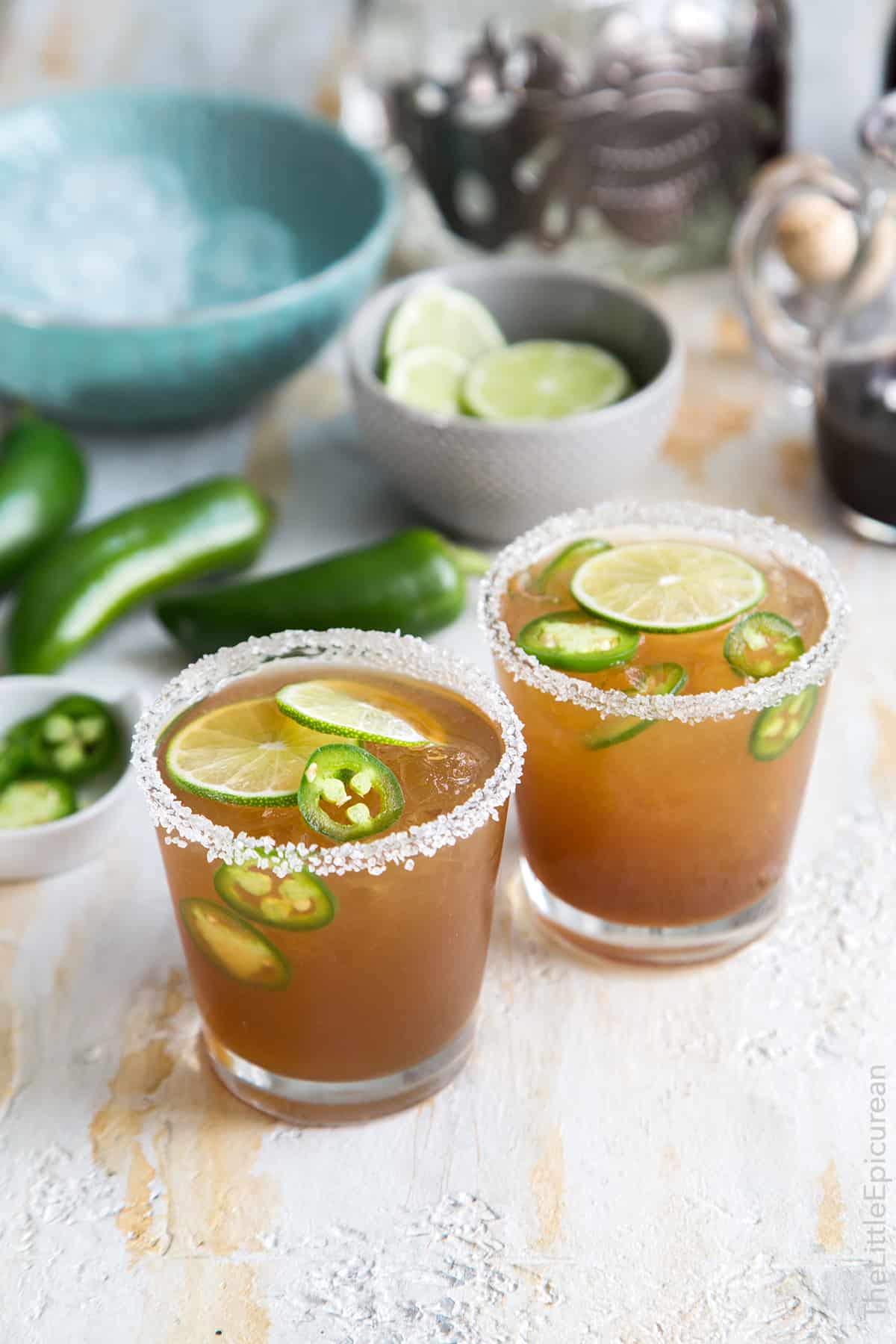 two servings of salt rimmed jalapeno margarita garnished with lime wheels. 