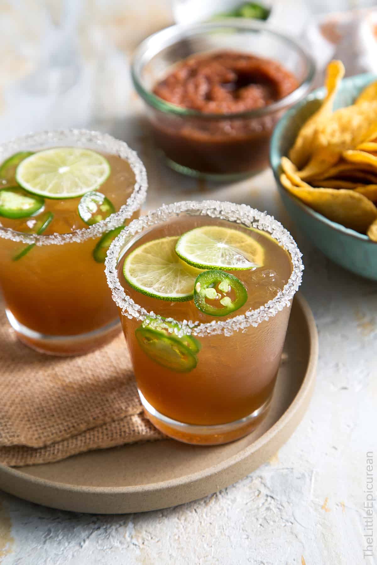 Spicy Jalapeno Margarita rimmed with salt on brown serving plate. 