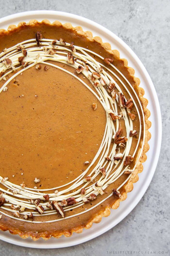 Easy Pumpkin Tart. Tart shell is made with a buttery shortbread crust. The one bowl pumpkin filling is a breeze to a make. It's decorated with melted white chocolate and chopped pecans. #pumpkin #pumpkintart #piesandtarts #dessert #thanksgiving