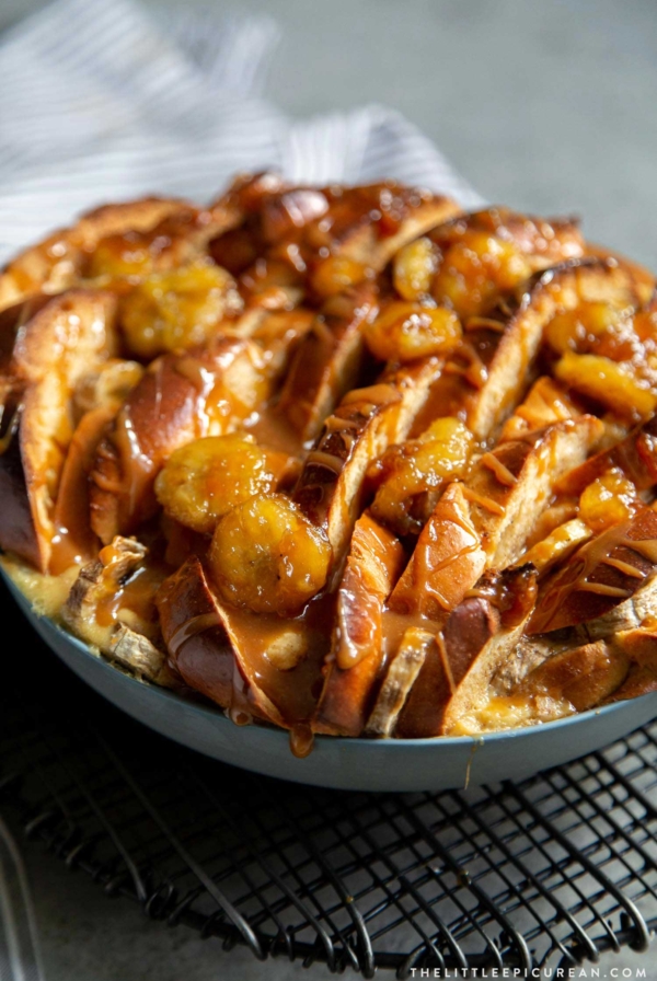 Banana Foster Bread Pudding. Sliced challah bread soaked in spiced custard mixture, baked until golden, and topped with brown sugar cooked bananas and caramel sauce. #breakfast #brunch #breadpudding #dessert #sweet