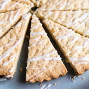 lemon shortbread cookie wedges topped with lemon glaze on blue plate.