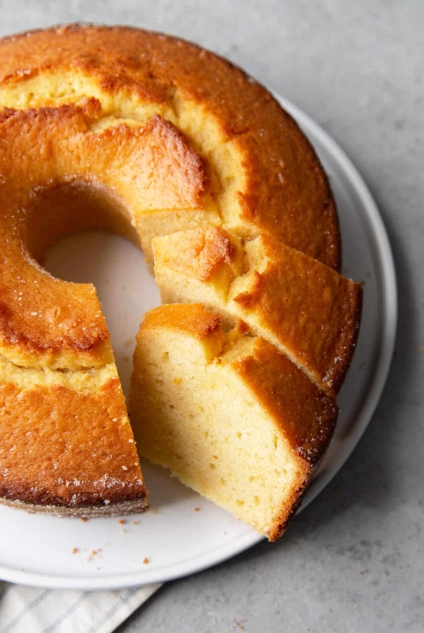 orange juice cake with slices cut out on white serving plate.